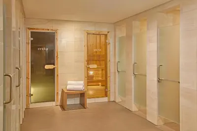 a bathroom with a walk in shower and a bench at Grand Westside Manila Bay in Manila