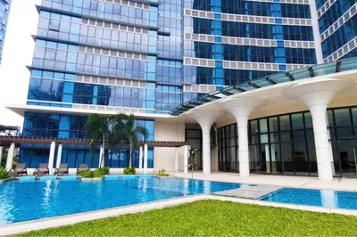a swimming pool in front of a tall building at Executive Gem beside Malls and Bars at Uptown BGC in Manila