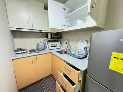 a small kitchen with white cabinets and a refrigerator at Executive Gem beside Malls and Bars at Uptown BGC in Manila