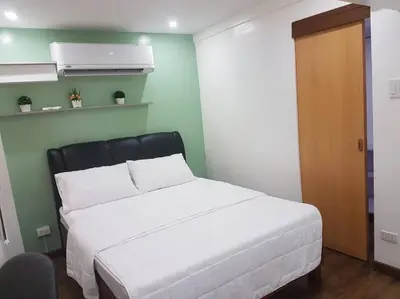 a bedroom with a white bed and a wooden door at Loft Style Condo Unit in Makati with Netflix WIFI in Manila