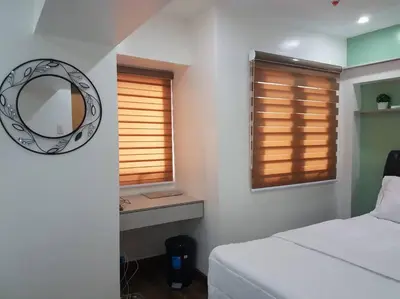 a bedroom with a bed and a mirror and a window at Loft Style Condo Unit in Makati with Netflix WIFI in Manila