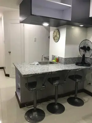 a kitchen with a counter with stools and a sink at Loft Style Condo Unit in Makati with Netflix WIFI in Manila