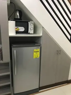 a small kitchen with a microwave and a refrigerator at Loft Style Condo Unit in Makati with Netflix WIFI in Manila