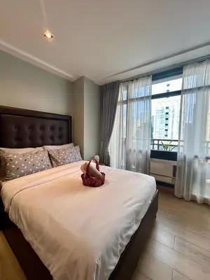 a doll sitting on a large bed in a bedroom at Quiet Condo with Fast WiFi, Own Balcony, Pool and Gym in Manila