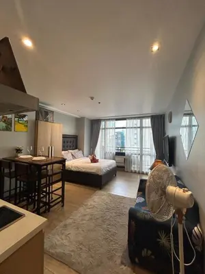 a large living room with a bed and a kitchen at Quiet Condo with Fast WiFi, Own Balcony, Pool and Gym in Manila