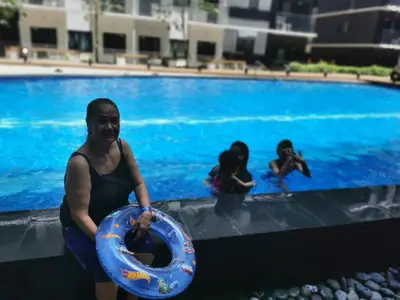 a man sitting in a swimming pool holding a lifesaver at Shore 3 residence Moa Pasay in Manila