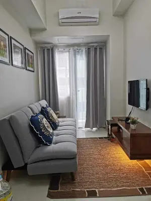 a living room with a couch and a television at Shore 3 residence Moa Pasay in Manila