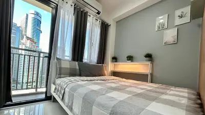 a bedroom with a bed and a large window at Homey 1BR Skyline at Lush Residences, Makati City in Manila