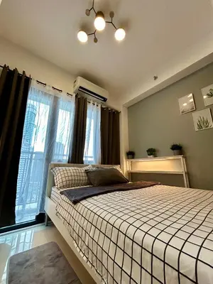 a bedroom with a large bed with windows at Homey 1BR Skyline at Lush Residences, Makati City in Manila