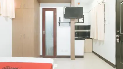 a room with a bed and a tv and a kitchen at RedDoorz at MGP Apartelle Near Espana in Manila