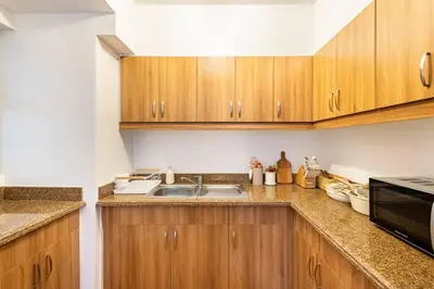 a kitchen with wooden cabinets and a sink at Coastal Inspired 2BR Condo I Fast Wi-Fi I Near BGC in Manila