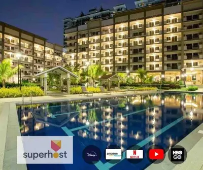 a hotel with a swimming pool in front of a building at Coastal Inspired 2BR Condo I Fast Wi-Fi I Near BGC in Manila