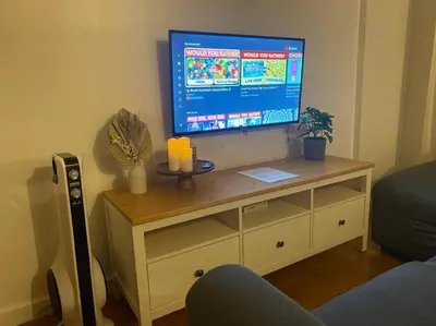 a television on a wooden stand in a living room at Coastal Inspired 2BR Condo I Fast Wi-Fi I Near BGC in Manila