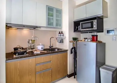 a kitchen with a refrigerator and a microwave at 1Up Retreat at BGC, Cinema Style near Mall in Manila