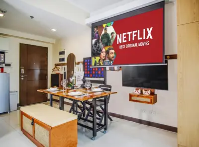 a television on a wall in a room with a table at 1Up Retreat at BGC, Cinema Style near Mall in Manila