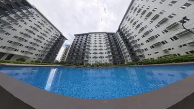 two tall buildings with a large blue swimming pool at UrbanEase Living at Charm Residences Near Sta Lucia Mall and Robinsons Mall in Manila