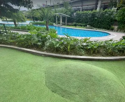 a large pool with a green lawn next to a building at La Mari 1 bedroom at Prisma Residences in Manila