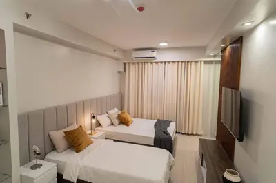 a hotel room with two beds and a television at Shore 2 Residences in Manila