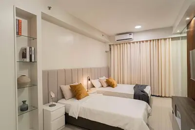 a bedroom with two beds and a television in it at Shore 2 Residences in Manila
