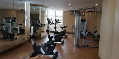 a gym with treadmills and ellipticals in front of a mirror at 101 Newport Boulevard in Manila
