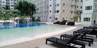 a large swimming pool in a building with chairs at 1 BR Condo with Balcony in Manila