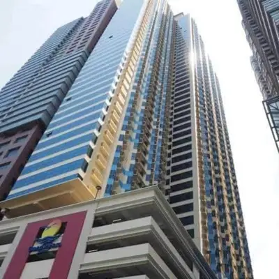 a tall building with the sun shining on it at Grand Riviera suite Condotel Near SLEC in Manila