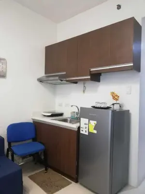 a small kitchen with a refrigerator and a blue chair at Grand Riviera suite Condotel Near SLEC in Manila