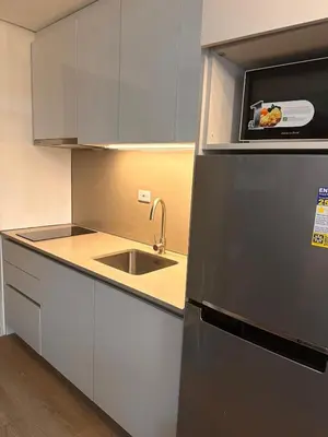 a kitchen with a sink and a refrigerator at Aya's Place Two Bedrooms near MOA in Manila