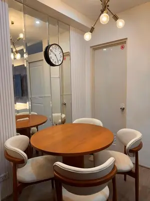 a dining room with a table and chairs and a clock at Aya's Place Two Bedrooms near MOA in Manila