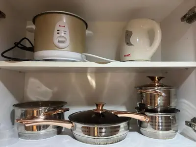 a stove with pots and pans on a shelf at Kendra Suite at Shore 3 Residences, MOA in Manila