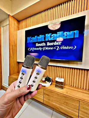 a person holding two microphones in front of a tv at Kendra Suite at Shore 3 Residences, MOA in Manila