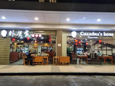 a restaurant with people sitting at tables in front of it at Cozy Shore Residence with balcony near Mall of Asia & airport in Manila