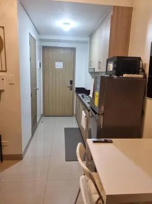 a kitchen with a refrigerator and a door to a hallway at Cozy Shore Residence with balcony near Mall of Asia & airport in Manila