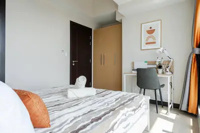 a bedroom with a bed with a chair and a desk at BGC Skyline 2BR Suite with Parking in Uptown BGC in Manila