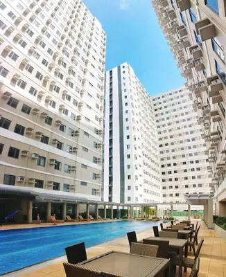 a large building with a pool and tables and chairs at 1014 - Cavite Minimalist Condo with Resort-like Amenities & Hi Speed Wifi in Dasmariñas