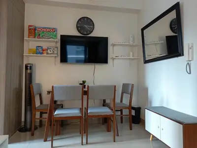 a dining room with a table and chairs and a tv at Shore 2 Residences high speed Internet walking distance to MOA and IKEA in Manila