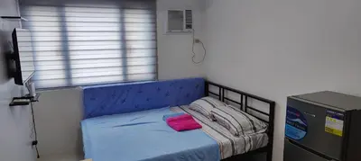 a small bed with a blue head board in a room at Grand Riviera Suites in Manila