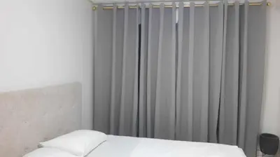 a bedroom with a bed and a window with curtains at WNSuites in Manila