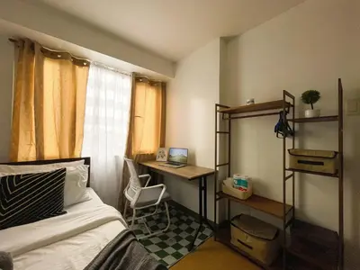 a bedroom with a bed and a desk with a laptop at Affordable Condo Near Bgc, Venice Mall #rt33006 in Manila