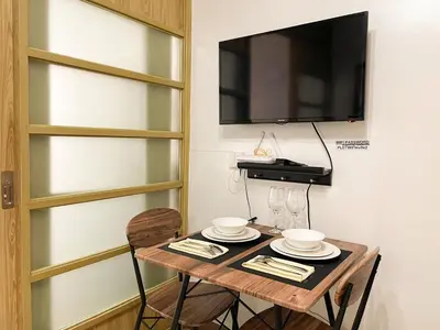 a table with two chairs and a television on a wall at Affordable Condo Near Bgc, Venice Mall #rt33006 in Manila