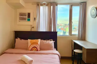 a bedroom with a bed with a desk and a window at Budget-friendly Condo Near Bgc, Venice #rt34008 in Manila