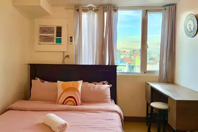 a bedroom with a bed with a desk and a window at Budget-friendly Condo Near Bgc, Venice #rt34008 in Manila