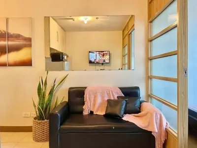 a black leather couch in a living room with a mirror at Budget-friendly Condo Near Bgc, Venice #rt34008 in Manila