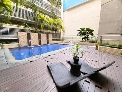 a black chair sitting on a deck next to a pool at 1Bedroom Accommodation Near Airport in Manila