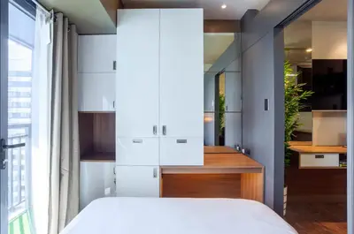 a bedroom with white cabinets and a large window at COZY SKYLINE CONDO in MAKATI in Manila