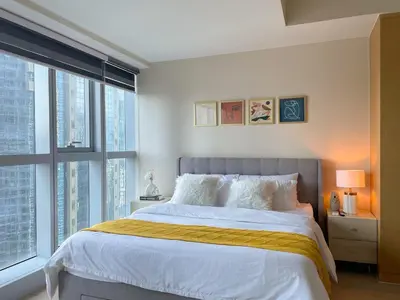 a bedroom with a large bed and a large window at Chic BGC Condo Near Uptown Parade #upt124r in Manila