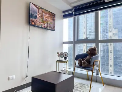 a teddy bear sitting in a chair in front of a window at Chic BGC Condo Near Uptown Parade #upt124r in Manila