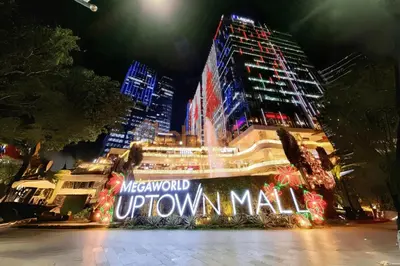 a building with a sign that reads metropolitan uptown mall at night at Chic BGC Condo Near Uptown Parade #upt124r in Manila