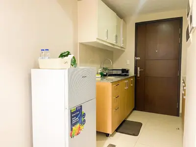 a small kitchen with a refrigerator and a door at Prime BGC 1BR Near Mitsukoshi Mall #upt16m in Manila