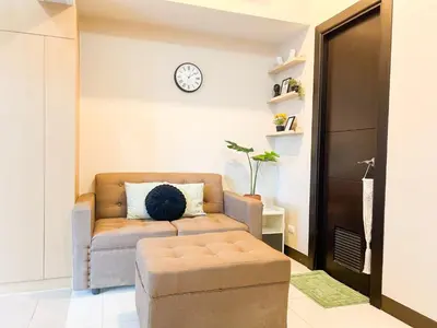a living room with a couch and a clock on the wall at Upscale BGC Stay Near Mitsukoshi #upt130g in Manila